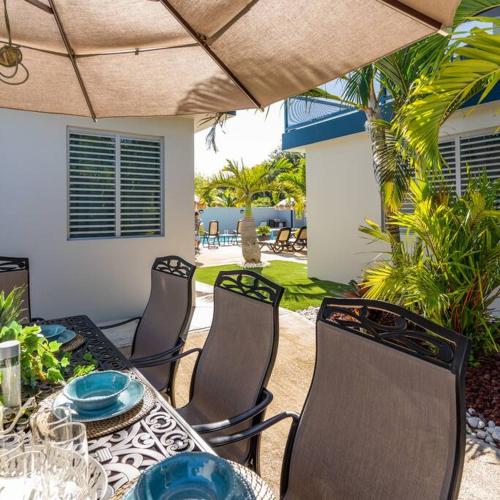 an outdoor table with chairs and a table with blue plates at Aquaville Dorado Moderna Villa 3 in Dorado