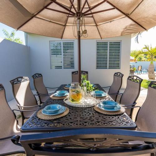 a dining table with chairs and an umbrella at Aquaville Dorado Moderna Villa 3 in Dorado