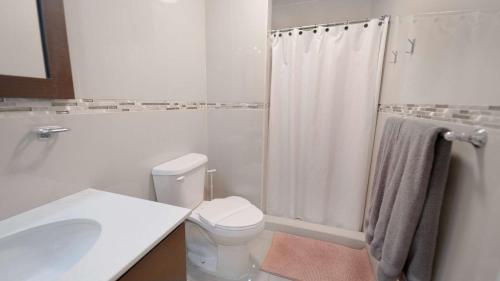 a white bathroom with a toilet and a sink at Aquaville Dorado Moderna Villa 3 in Dorado