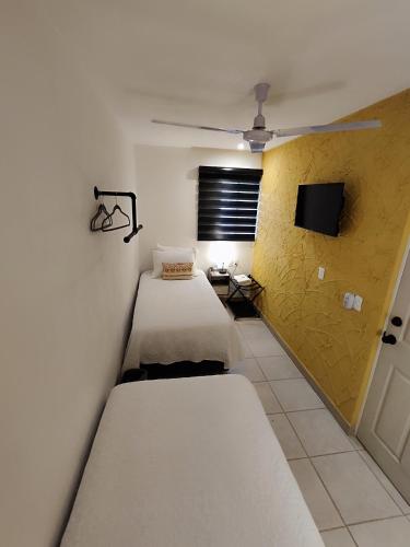 two beds in a room with a yellow wall at Casa Aceves & Bueno Hotel Boutique in El Salto