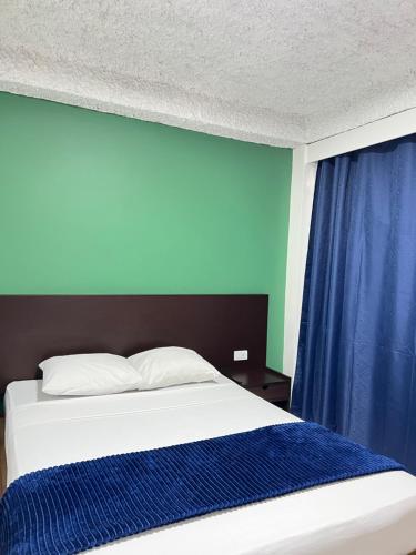 a bedroom with a bed with a blue wall at Hotel Grand Galaxie in Caracas