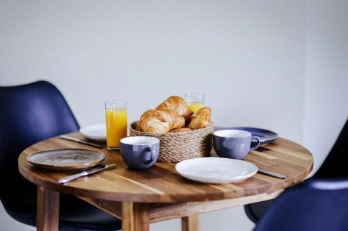 a table with a basket of croissants and orange juice at Zentral, bis zu 6Pers, salt apartments Weissenfels in Weißenfels