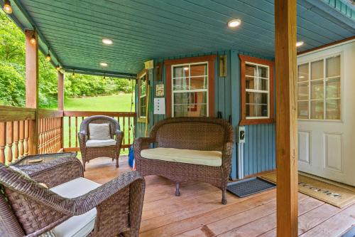a covered porch with wicker chairs and a table at River Crossing Tiny Cabin in Beattyville
