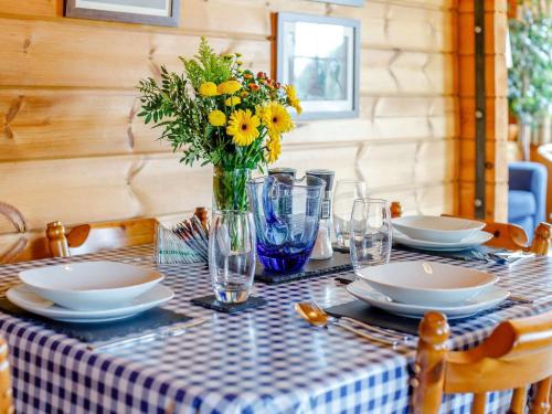 a table with plates and a vase of yellow flowers at 2 Bed in Blandford Forum 61027 in Child Okeford