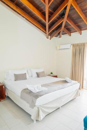 a bedroom with a large white bed with wooden ceilings at Hotel Playa Palmeras Cartagena - Vía al Mar in Cartagena de Indias