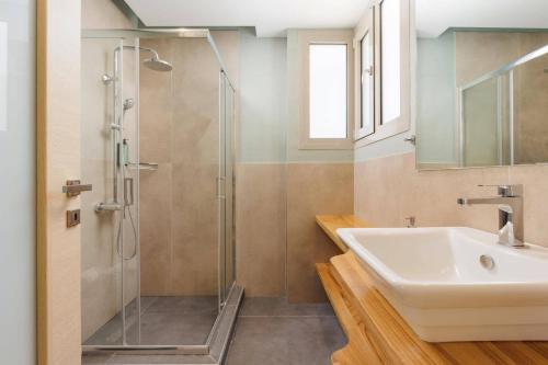 a bathroom with a glass shower and a sink at Villa Daphne Gouvia by Villa Plus in Gouvia