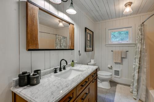 a bathroom with a sink and a toilet and a mirror at Chic Highlands Cabin Retreat with Deck and Office! in Highlands