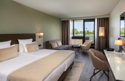a hotel room with a large bed and a desk at Leonardo Hotel Hannover in Hannover