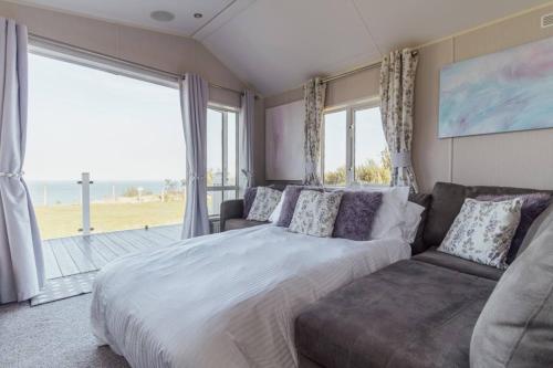 a bedroom with a large bed and a couch at Beautiful lodge - stunning sea views, dog friendly in Eastchurch