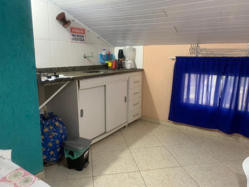 a kitchen with white cabinets and a blue curtain at Kitnet Pontal Beach in Arraial do Cabo