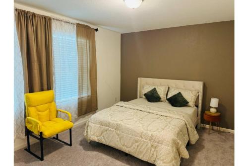 a bedroom with a bed and a yellow chair at Fenced Yard • Foosball • Putting Green in Crowley