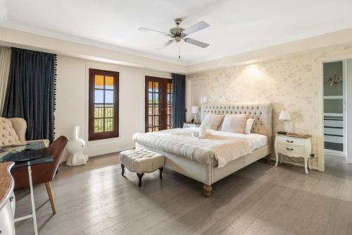 a white bedroom with a large bed and a desk at Luxe Villa Spacious Family Home with Pool and Patio in Brisbane