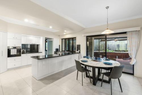 a kitchen and dining room with a table and chairs at Luxe Villa Spacious Family Home with Pool and Patio in Brisbane