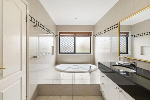 a white bathroom with a tub and a sink at Luxe Villa Spacious Family Home with Pool and Patio in Brisbane