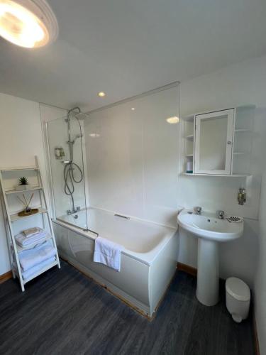 a white bathroom with a tub and a sink at Caledonian House Apartment in Fort William