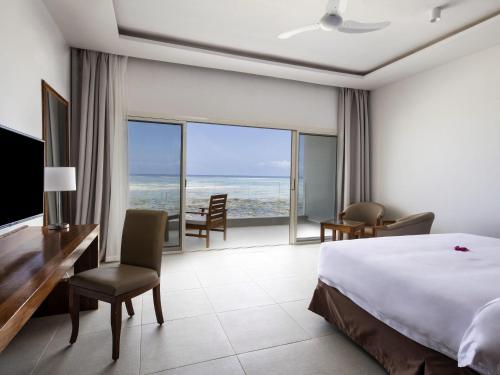 a bedroom with a bed and a desk and a view of the ocean at Nungwi Dreams by Mantis in Nungwi