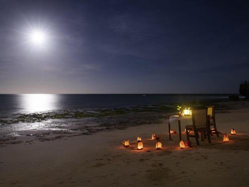 a table and chairs on the beach at night at Nungwi Dreams by Mantis in Nungwi