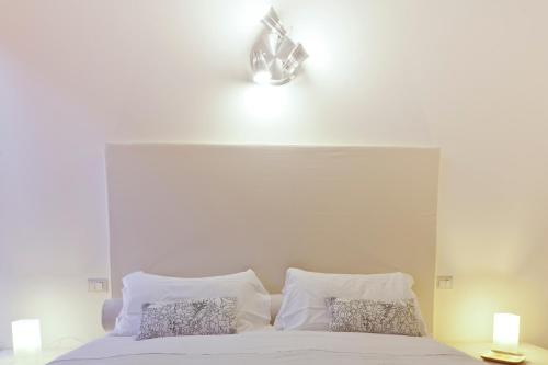 a white bed with a white headboard and two pillows at Exclusive Aparthotel La Reunion in Ravenna
