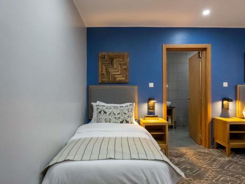 a bedroom with a bed and a blue wall at Mantis Akagera Game Lodge in Akagera