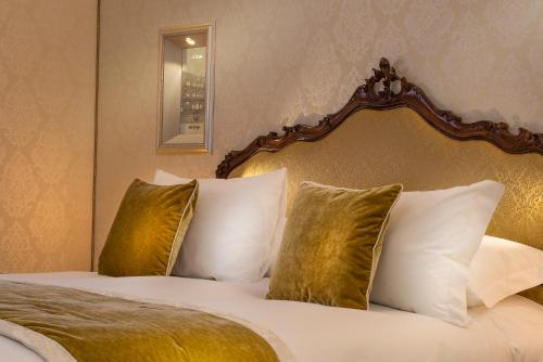a bedroom with a bed with four pillows at Papadopoli Hotel Venezia - MGallery Collection in Venice