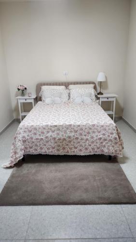 a bedroom with a bed with a floral bedspread at צימר החורש in Dāliyat el Karmil