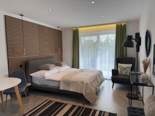 a bedroom with a bed and a chair and a window at Kal's Studio Apartment Salzburg in Salzburg
