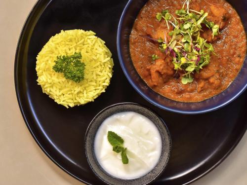 a black plate with two bowls of food and rice at Vivari Hotel and Spa by Mantis in Johannesburg