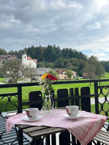 a table with two cups and a vase with flowers at Apartments Bukor with seasonal pool in Lukovica pri Domžalah