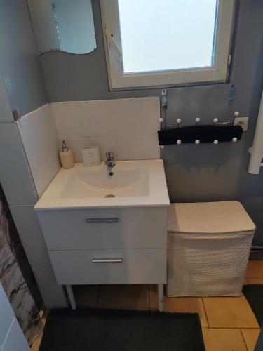 een badkamer met een witte wastafel en een raam bij Maison mignonne in Hirson