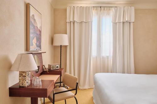 a bedroom with a bed and a desk and a window at Hôtel Le Provençal - Rénové en 2025 - Bord de Mer in Hyères