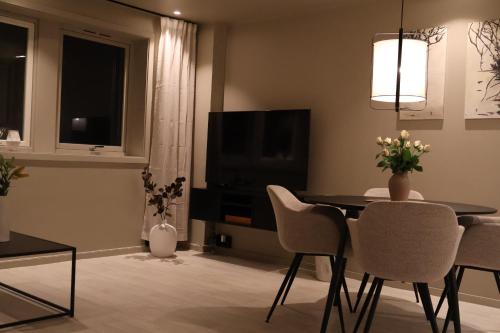 a living room with a table and chairs and a television at Arctic City Suites 2 in Kirkenes