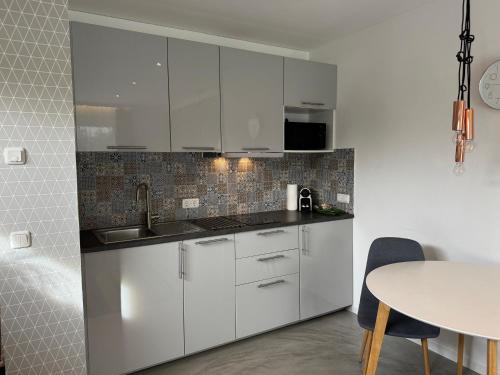 a white kitchen with white cabinets and a table at Kal's Studio Apartment Salzburg in Salzburg