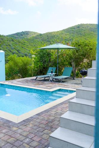 una piscina con dos sillas y una sombrilla en Beach House, Tranquil Santirome Studio 2, en Westpunt