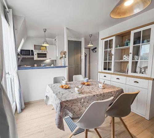 a kitchen and dining room with a table and chairs at Un souffle marin dans ce F2 à Cabourg in Cabourg
