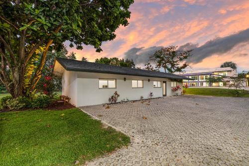 a white house with a tree and a gravel driveway at Modani Estates in Miami