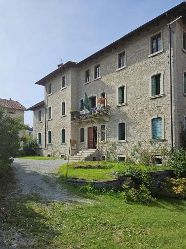 a large stone building with a yard in front of it at La casa di Mel in Mel