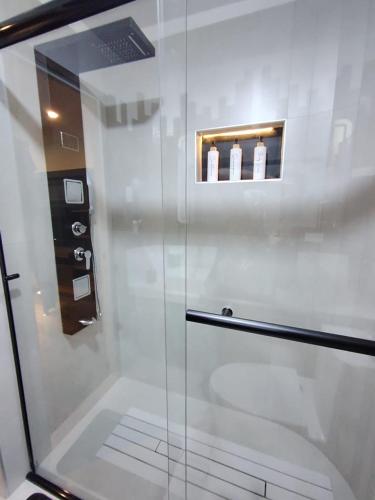 a glass shower door with three bottles on a shelf at Romántica Suite entre tules in Arequipa