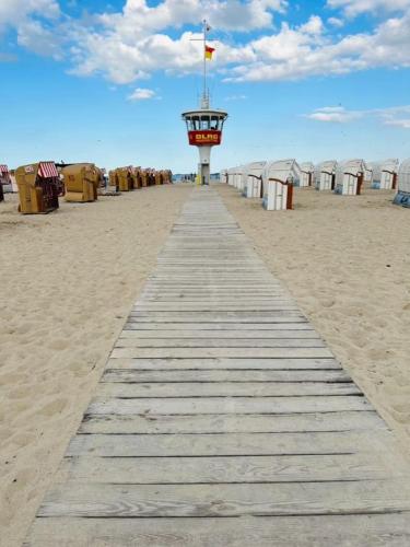 a boardwalk on the beach with a row of beach huts at Travemünde Ruheoase mit Pool Sauna Parkplatz in Rönnau