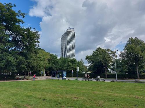a tall building in a park with people sitting on benches at Travemünde Ruheoase mit Pool Sauna Parkplatz in Rönnau