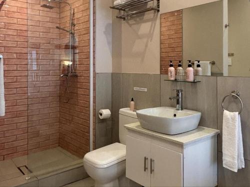 a bathroom with a toilet and a sink and a shower at La Casa Blanca in Johannesburg