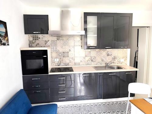 a kitchen with black cabinets and a sink at Paradise Home just a few minutes from Lake Maggiore in Gravellona Toce