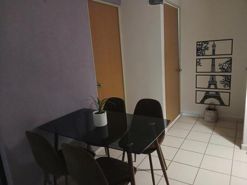 a dining room with a black table and chairs at Departamento Ganges in León