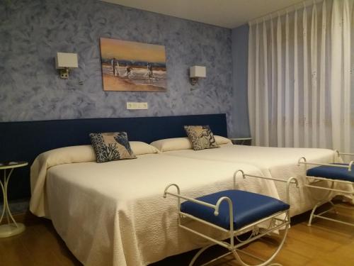 two beds in a room with blue walls at Hotel el Pinar in Villapedre