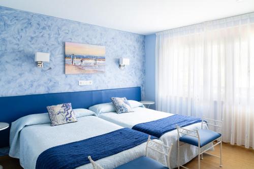 two beds in a bedroom with blue walls at Hotel el Pinar in Villapedre