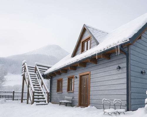 a blue house with snow on the roof at Telgártska chalupa pod Kráľovou hoľou - sauna & altánok in Telgárt