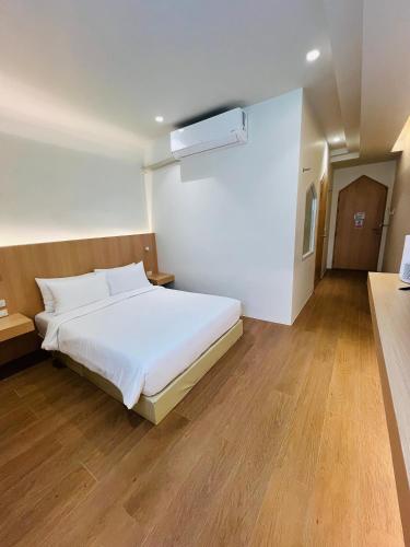 a bedroom with a white bed and wooden floors at Minitel at Hatyai in Ban Khlong Wa
