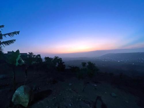 a sunset from the top of a hill with trees at 1 Bedroom Sunset & Mountain View Chalet in Aburi in Aburi