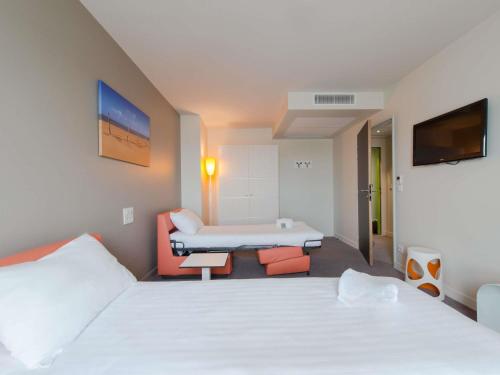 a hotel room with two beds and a couch at Hôtel Confort La Rochelle Centre les Minimes in La Rochelle