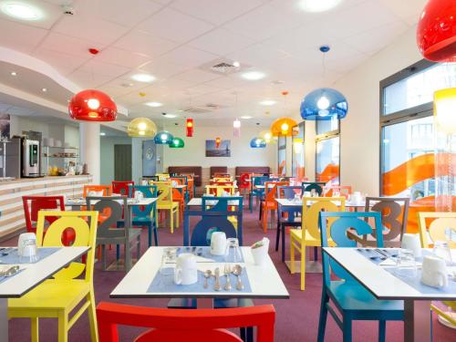 a restaurant with colorful tables and chairs at Hôtel Confort La Rochelle Centre les Minimes in La Rochelle