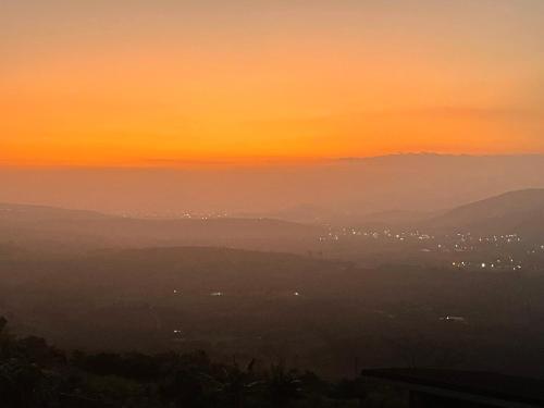 a sunset view of a city in the distance at 1 Bedroom Sunset & Mountain View Chalet in Aburi in Aburi